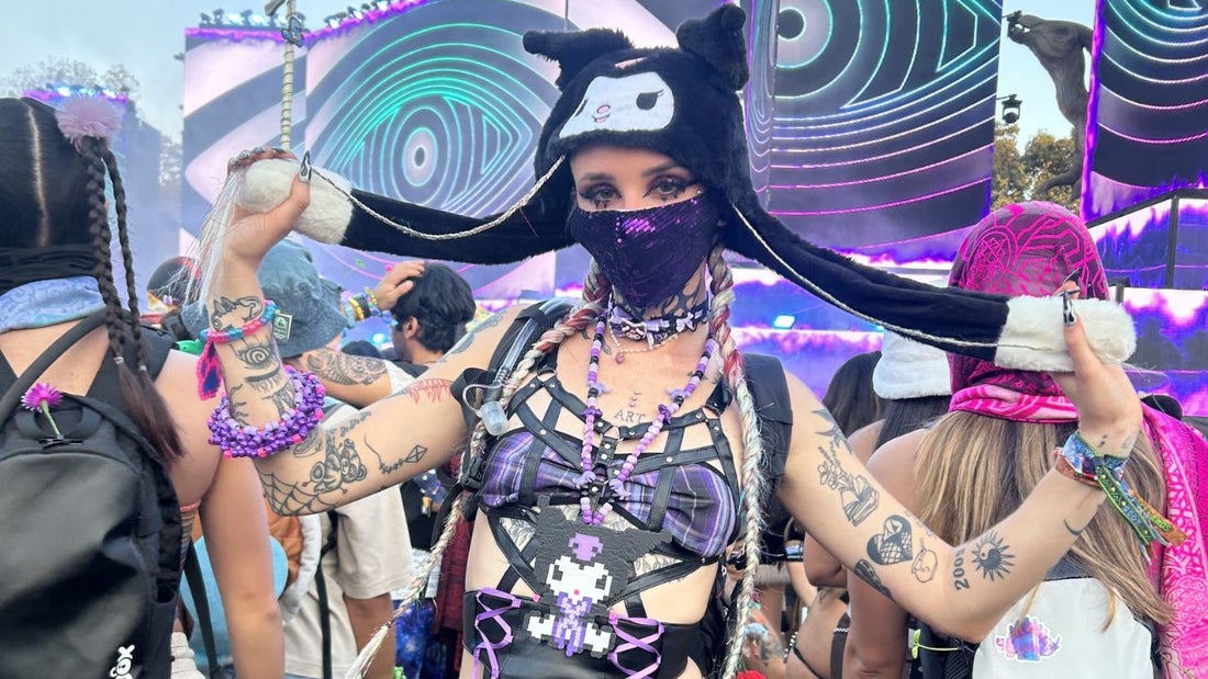 Festival-goers in rave outfits enjoying a music festival main stage at sunset