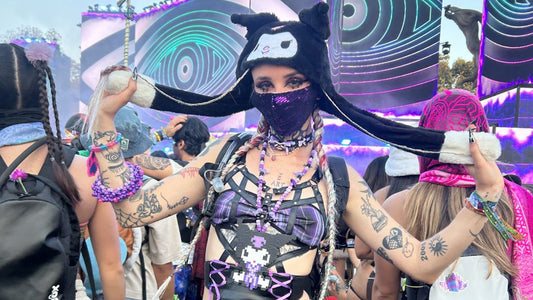 Festival-goers in rave outfits enjoying a music festival main stage at sunset