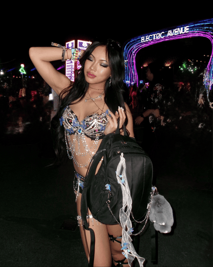 Woman in a sparkling outfit at a music festival with 'Electric Avenue' sign in the background