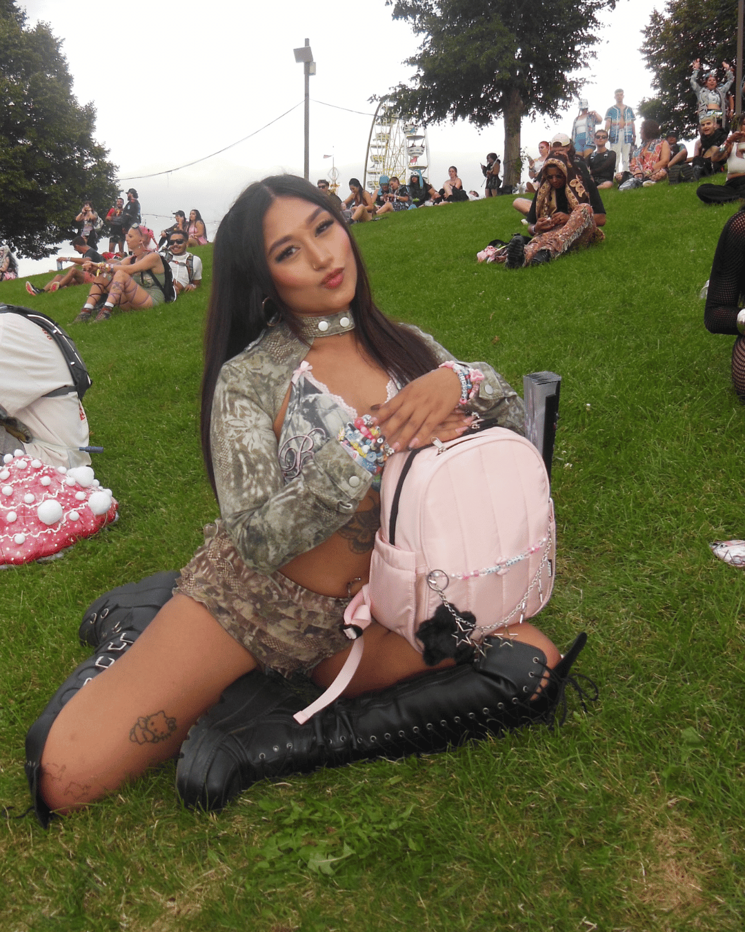 Woman sitting on grass with a pink backpack at an outdoor event